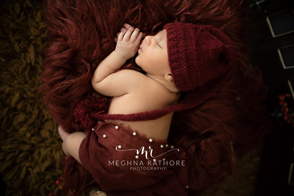 24 days old newborn baby boy posing adorably in cute outfit top angle shot in professional photoshoot set up at Meghna Rathore photography in gurgaun, new delhi and noida