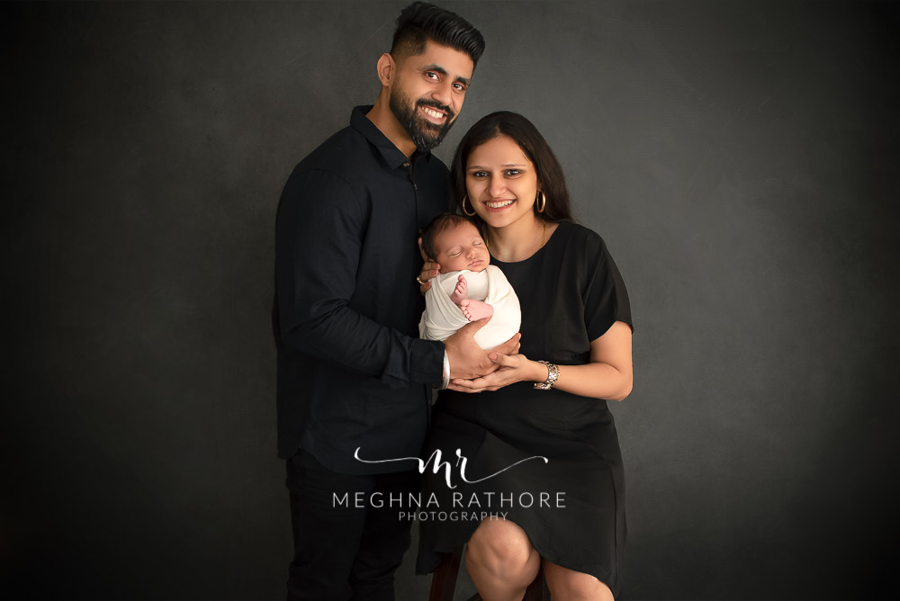 24 days old newborn baby boy posing with father and mother in professional photoshoot set up at Meghna Rathore photography in gurgaun, new delhi and noida