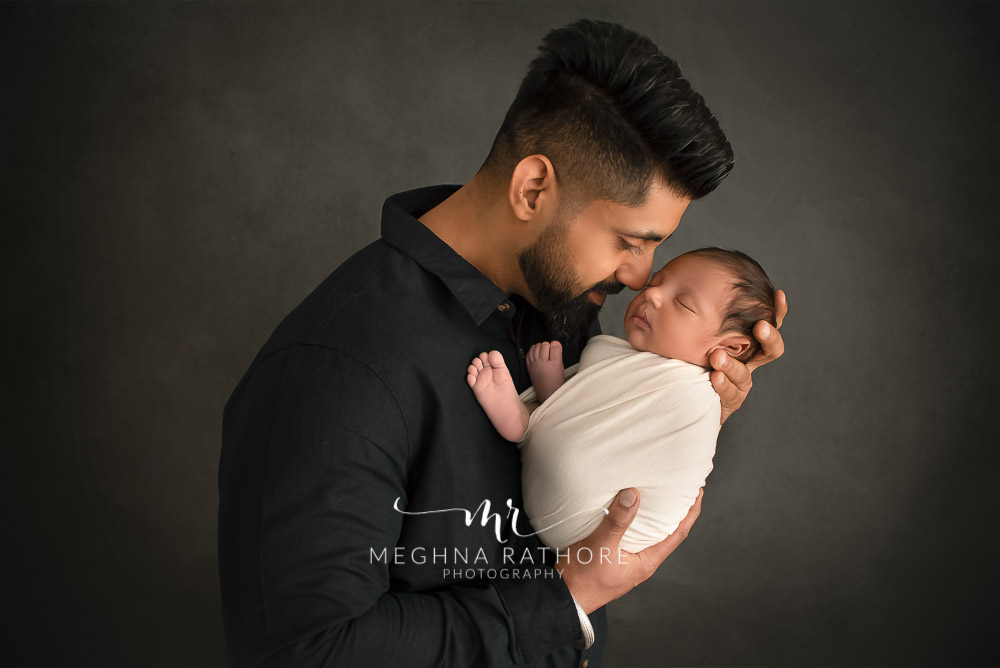 24 days old newborn baby boy posing with father in professional photoshoot set up at Meghna Rathore photography in gurgaun, new delhi and noida