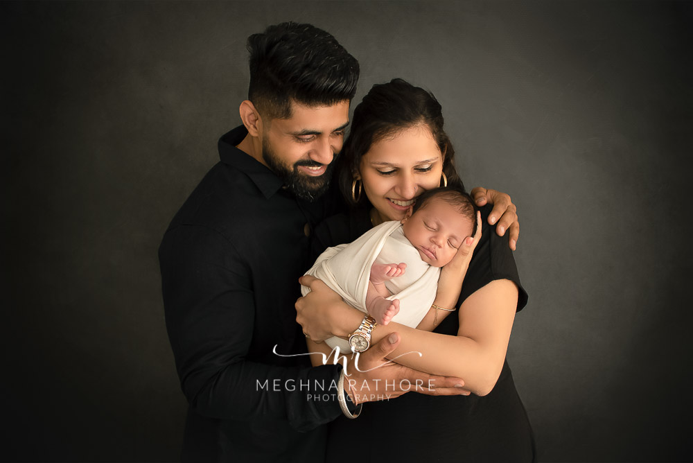 24 days old newborn baby boy posing with father and mother in professional photoshoot set up at Meghna Rathore photography in gurgaun, new delhi and noida