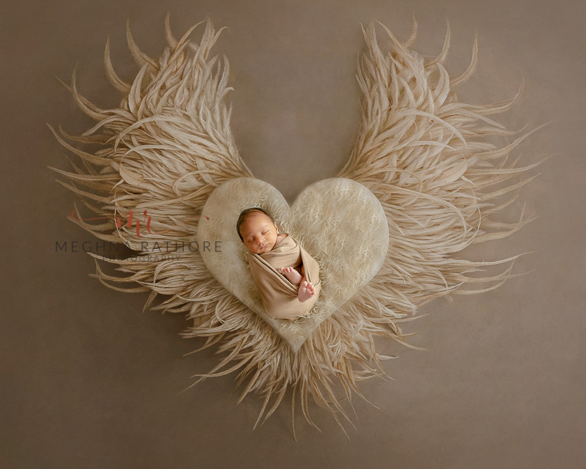 24 days old newborn baby boy posing adorably with props around in professional photoshoot set up at Meghna Rathore photography in gurgaun, new delhi and noida